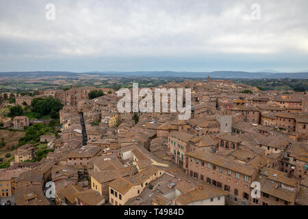 Panoramic view of Siena city with historic buildings and far away green fields from Torre del Mangia is a tower in city. Summer sunny day and dramatic Stock Photo