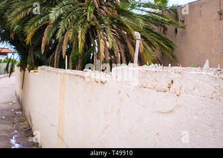 Wall-fence with shards of bottles and water pipes on top. Stock Photo