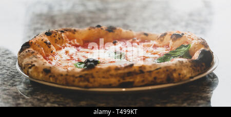 Selective focus of margherita pizza in plate on marble top. Stock Photo