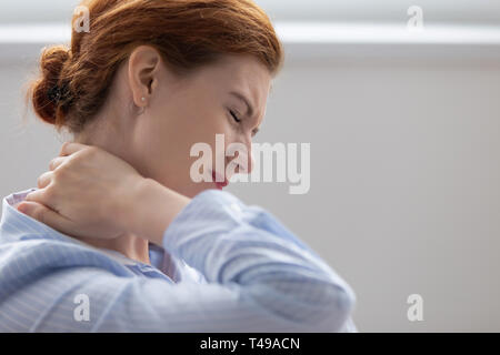 Tired fatigued business woman feeling hurt rubbing stiff neck Stock Photo