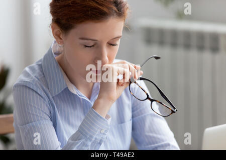 Tired business woman holding glasses taking break for eyes rest Stock Photo