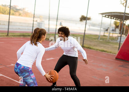 Group of young multiethnic young people  playing basketball on court Stock Photo