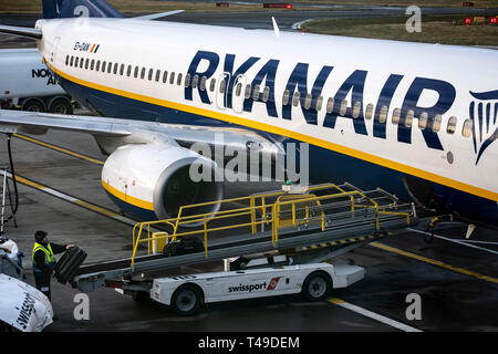 Bag handler loading suitcase onto Ryanair airplane Stock Photo