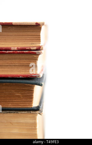 Old worn books stacked on white surface close up with copy space Stock Photo