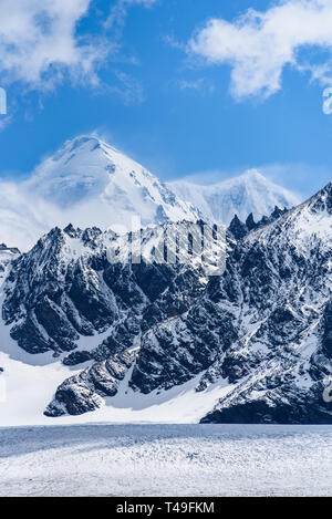 Beautiful blue sky day with snow covered mountain peaks, and wind blowing the snow, white and blue nature background, St. Andrews Bay, South Georgia Stock Photo