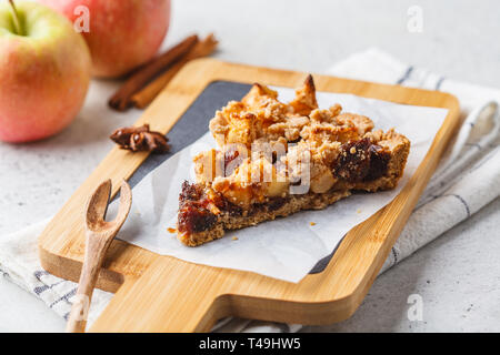 Piece of vegan apple pie with cinnamon on wooden board. Vegan food concept. Stock Photo