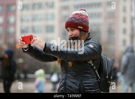 Chicago, USA. 14th Apr, 2019. A woman takes selfies in snow in Chicago, the United States, on April 14, 2019. A snowfall hit Chicago on Sunday. Credit: Wang Ping/Xinhua/Alamy Live News Stock Photo
