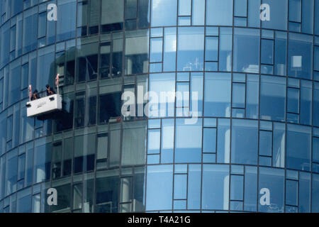 15 April 2019, Hessen, Frankfurt/Main: From a gondola, two window cleaners clean the facade of the Helaba Tower in the city centre. In the coming days, the weather will become increasingly sunny. Photo: Boris Roessler/dpa Stock Photo