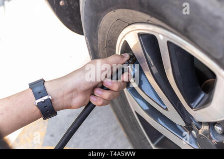A man checks the tire air pressure and filling air into a car tires. Stock Photo