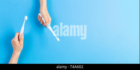 Kid hands with electric toothbrushes on blue background Stock Photo