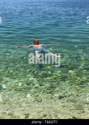 man swimming in a clear blue sea Stock Photo