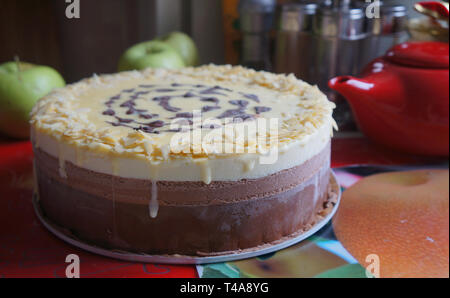 Homemade sweet chocolate cake near painted teapots, green apples and a samovar on the table Stock Photo