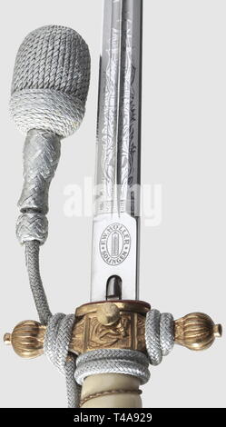A model 1938 dagger for naval officers, with portepee and hanger, Maker F.W. Höller, Solingen Nickel-plated blade with an etched, fouled anchor and sailing vessels amid tendrils as well as an etched manufacturer's mark on the ricasso. Crossguard and pommel with partially preserved gilding. White plastic grip with wire winding. Push-button scabbard release. The scabbard decorated with 'thunder-bolt' pattern and well-preserved gilding. Length 38 cm. Silver portepee. The hanger of black ribbed silk with black velvet lining and aluminium fittings (administrative official). In b, Editorial-Use-Only Stock Photo