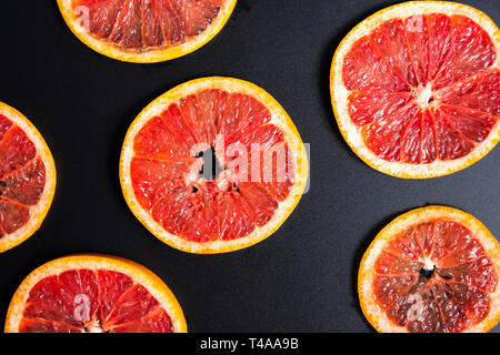Sliced grapefruit on a dark background making pattern Stock Photo