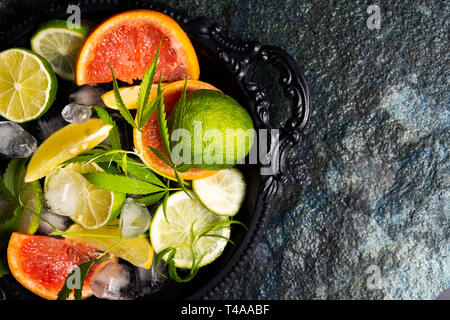 Sliced citrus fruits and marijuana on a plate top view Stock Photo