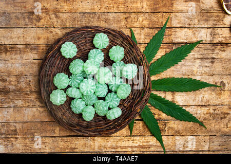 Cannabis bonbons and marijuana leafs on a table top view Stock Photo
