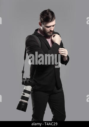 professional photographer with camera, adjusting a cufflink.isolated on grey background Stock Photo