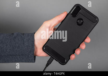 Mans hand holding black mobile phone Stock Photo