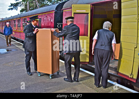 Broadway station staff in traditional uniforms, help unload goods from guardsvan compartment on train after arriving from Cheltenham Racecourse. Stock Photo