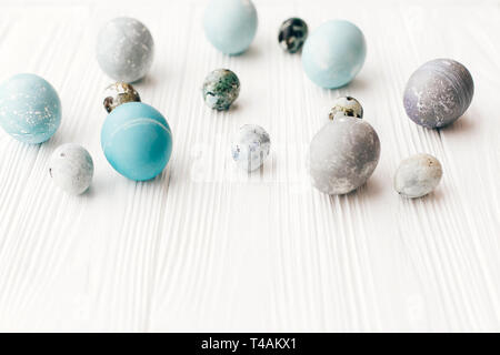 Stylish Easter eggs on white wooden background with space for text. Modern easter eggs painted with natural dye in blue and grey marble. Happy Easter, Stock Photo