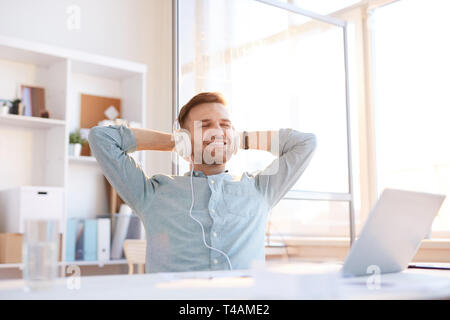 Young Man Listening to Music at Workplace Stock Photo
