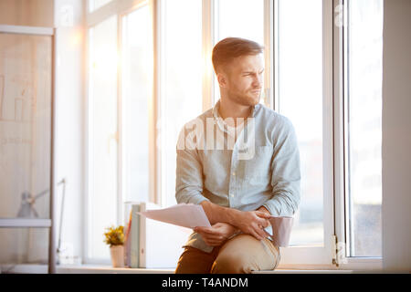 Pensive Businessman Sitting by Window Stock Photo