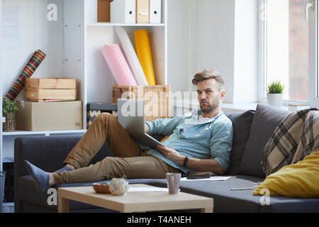 Handsome Man Using Laptop on Sofa Stock Photo