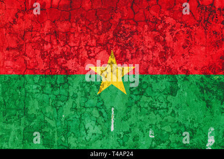 National flag of Burkina Faso on the background of the old wall covered with peeling paint. Concept of country, nation and patriotism symbol Stock Photo