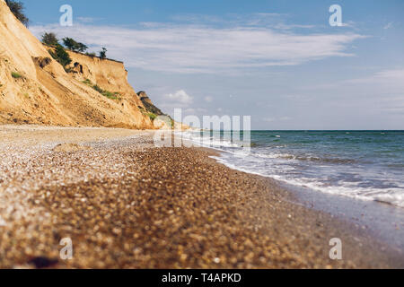 Beautiful view of sandy cliff near sea beach. Landscape of beach cliff and waves in sunny weather. Summer vacation concept. Exploring interesting plac Stock Photo