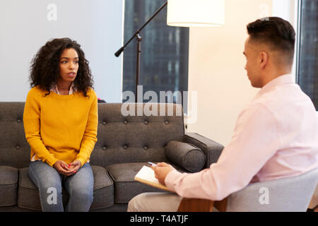 Woman Sitting On Couch Meeting With Male Counsellor In Office Stock Photo