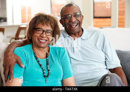 Senior black couple sitting at home, smiling to camera, close up Stock Photo