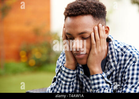 Depressed young black man with head in hands, close up, head and shoulders Stock Photo