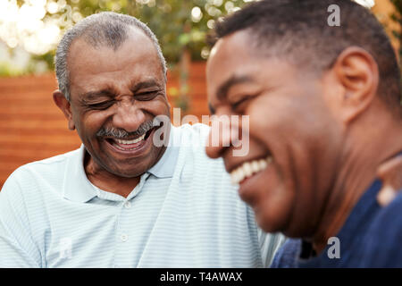 Senior black man and his adult son laughing together outdoors, close up Stock Photo