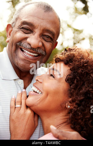 Senior black man and his middled aged daughter embracing and laughing, vertical Stock Photo