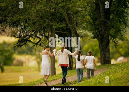 Mature woman walking and holding hands with her daughters. Stock Photo