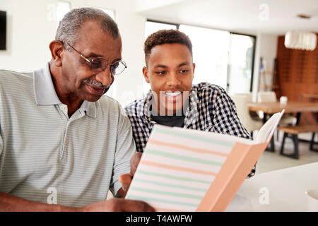 Young black man looking at a photo album at home with his grandfather, close up Stock Photo