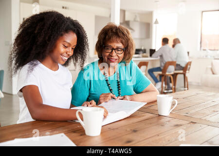 Teenage black girl looking through a photo album with her grandmother at home, close up Stock Photo
