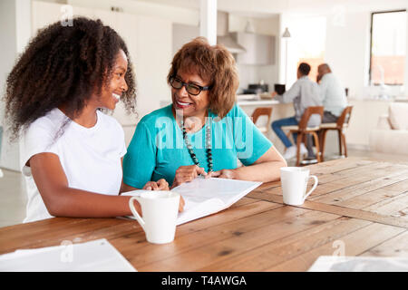 Teenage black girl and her grandmother looking through a photo album smiling at each other, close up Stock Photo