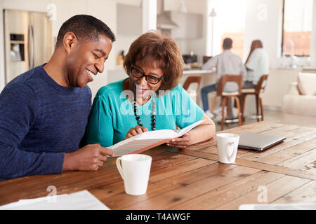 Middle aged black man looking through a photo album with his mother at home, close up Stock Photo