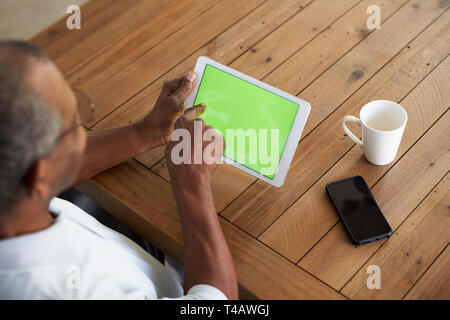 Senior black man sitting at table using tablet computer, elevated over shoulder view Stock Photo