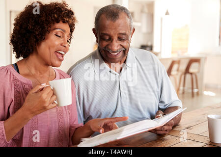 Senior black man and his middle aged daughter looking through photo album together at home, close up Stock Photo