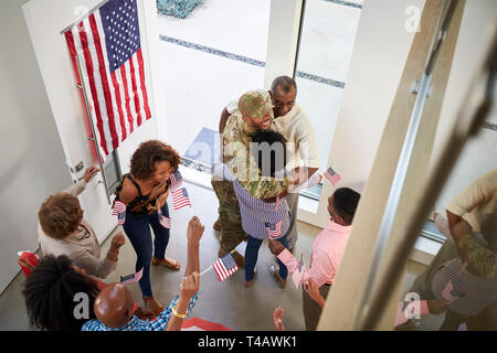 Young black male soldier welcomed home by three generation family, elevated view Stock Photo