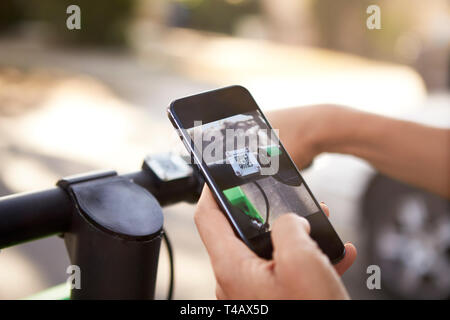 Close up of woman's hands using smartphone while riding on an electric scooter,detail Stock Photo