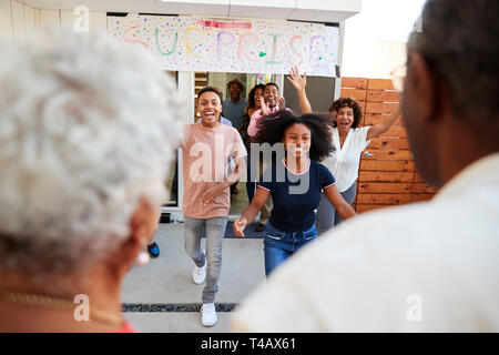 Over shoulder view of family running to welcome grandparents for a surprise family party Stock Photo