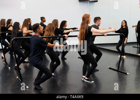 Students With Teacher At Performing Arts School Rehearsing Ballet In Dance Studio Using Barre Stock Photo