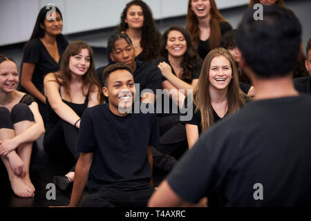 Teacher At Performing Arts School Talking To Students Sitting On Floor In Rehearsal Studio Stock Photo