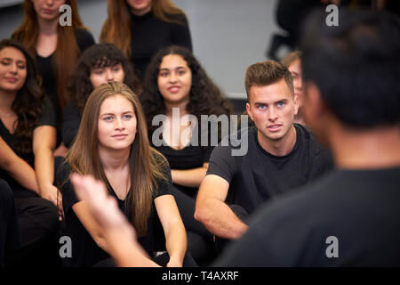 Teacher At Performing Arts School Talking To Students Sitting On Floor In Rehearsal Studio Stock Photo