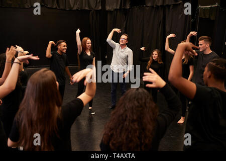 Teacher With Male And Female Drama Students At Performing Arts School In Studio Improvisation Class Stock Photo