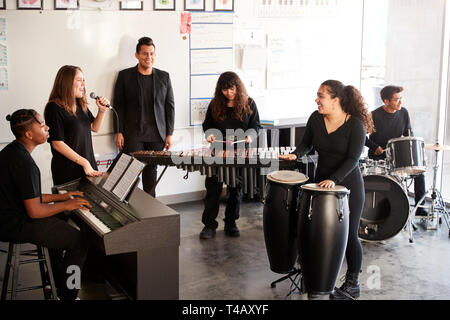 Students At Performing Arts School Playing In Band At Rehearsal With Teacher Stock Photo