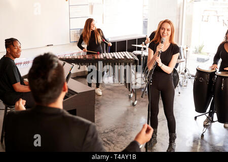 Students At Performing Arts School Playing In Band At Rehearsal With Teacher Stock Photo